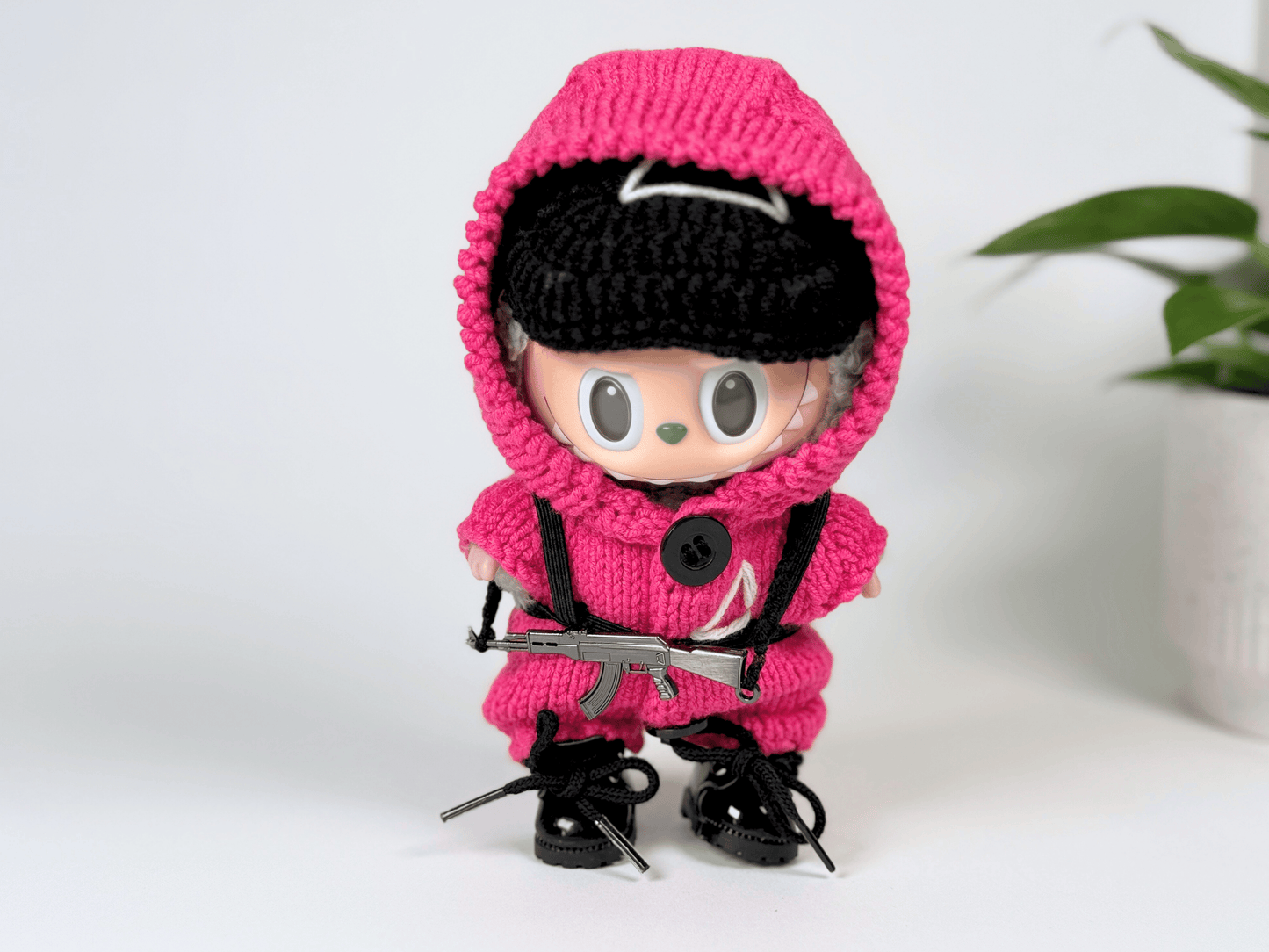Labubu doll with mask lifted, showing face while wearing complete handmade Squid Game pink guard outfit and accessories