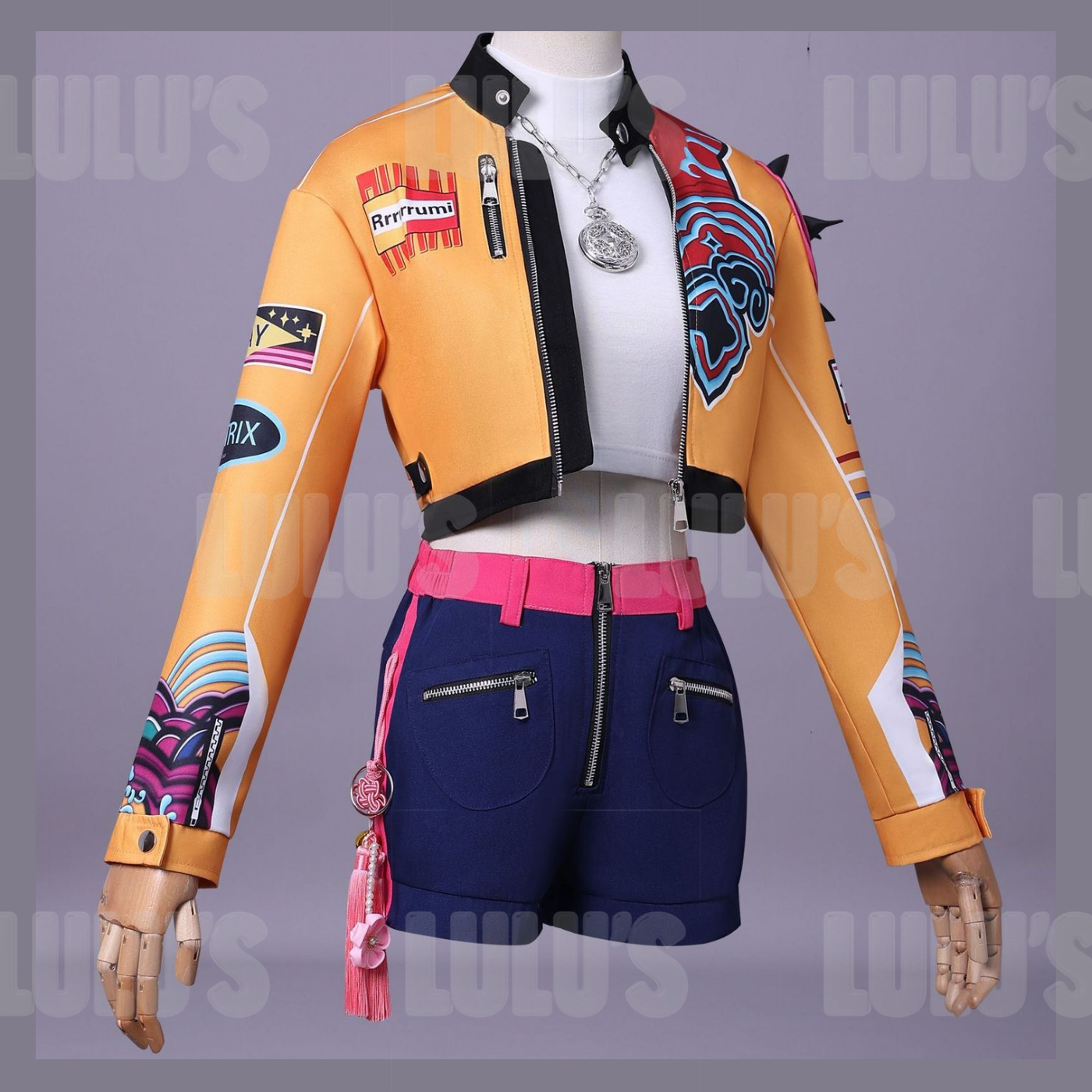 Front close-up of K-Pop Demon Hunters Rumi cosplay costume featuring orange cropped jacket with character patches, white crop top, and navy shorts with pink belt.