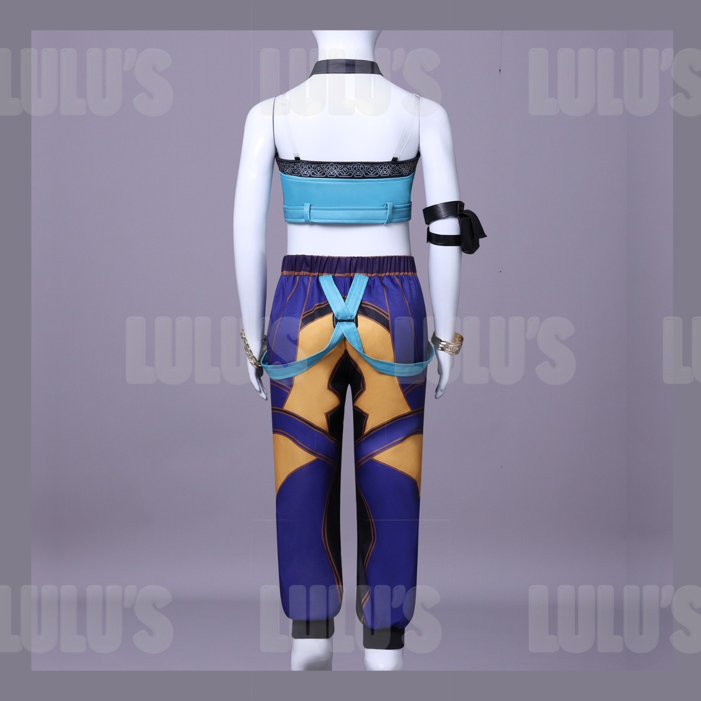 Back view of Zoey kids costume showing blue crop top straps and purple-gold pants with teal harness accents