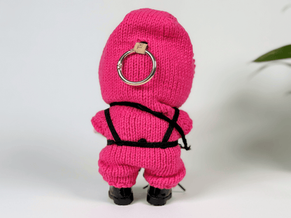 Back view of crochet Squid Game guard outfit on Labubu doll showing detailed black harness and pink hoodie with keyring