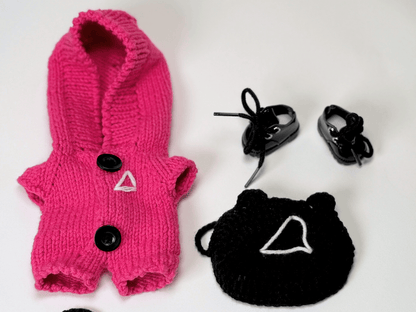 Close-up flat lay of Squid Game crochet costume set for Labubu with pink jumpsuit, triangle mask, vinyl boots, and accessories