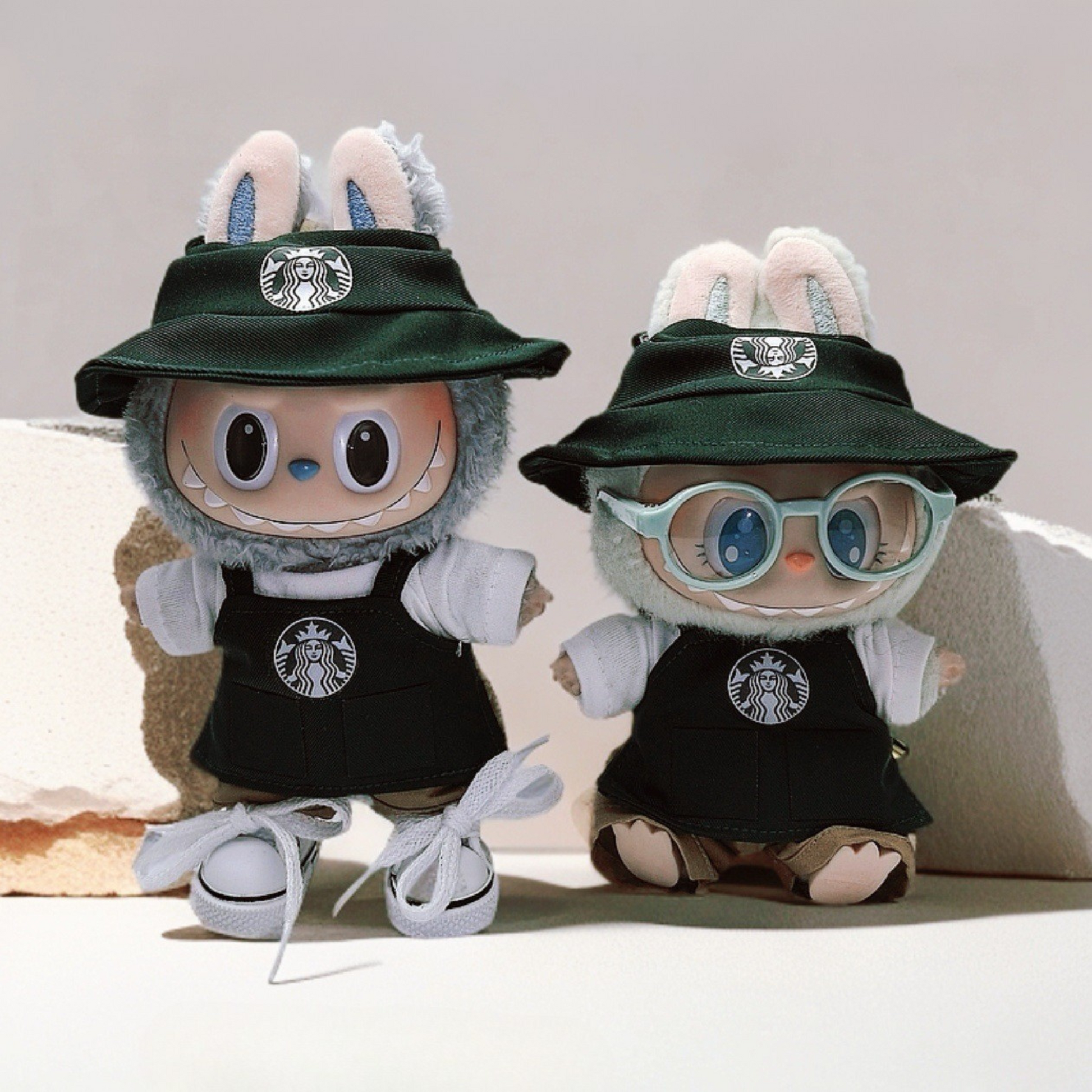 Two Labubu Dolls wearing a 3 and 4-piece starbucks uniform  and one Labubu wearing green glasses