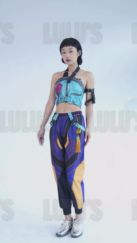 Video of a Model in K-Pop Demon Hunters Zoe cosplay costume striking character poses, featuring blue crop top, purple patterned jogger pants, tassel belt, and black arm band