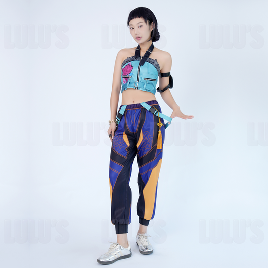 Model in K-Pop Demon Hunters Zoe cosplay costume striking character pose, featuring blue crop top, purple patterned jogger pants, tassel belt, and black arm band.